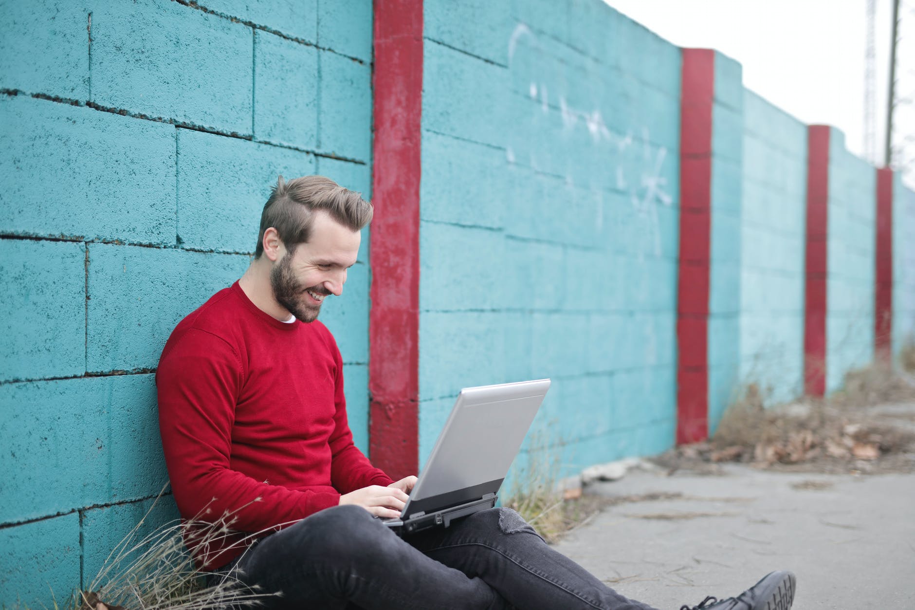 man leaning against wall using laptop